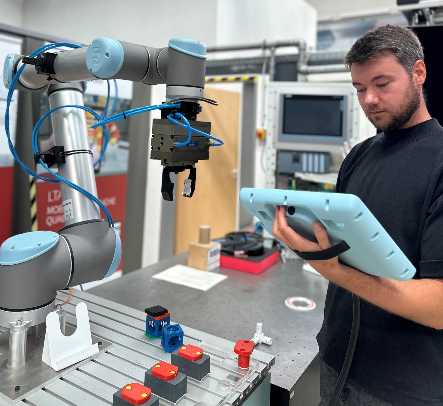 Programmierarbeitsplatz "Kollaborativer Roboter" Ein Mann mit Tablet steht neben einem Industrieroboter