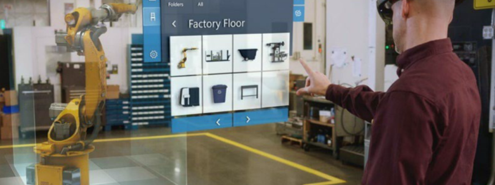 Eine Person mit aufgesetzter Augmented Reality Brille steht in einer Laborhalle und hält einen Arm ausgestreckt vor dem Körper und schaut auf eine virtuelle Umgebung