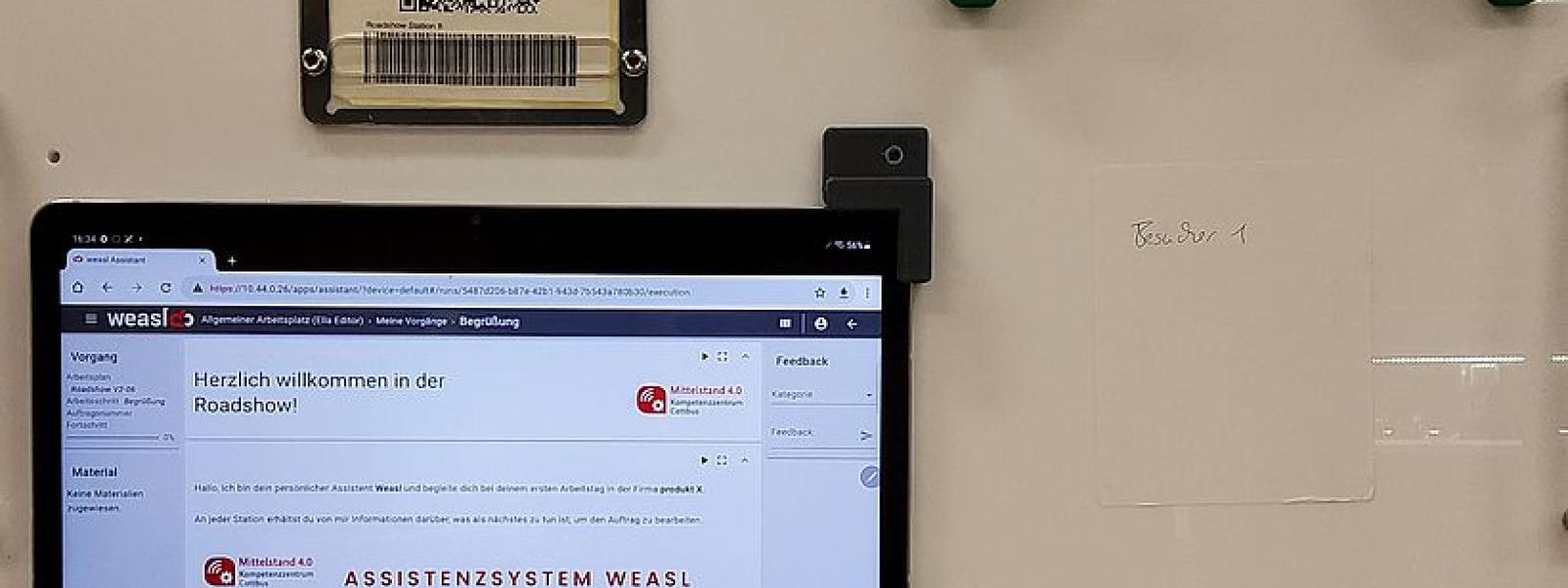 Ein Tablet, ein QR-Code und einige Formteile an einer Wand montiert