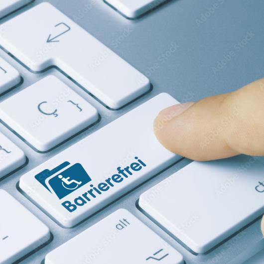 Nahaufnahme, rechte Tastaturbereich, Taste mit Aktenicon, Rollstuhl Icon und dem Wort Barrierefrei wird von einem Finger gedrückt.