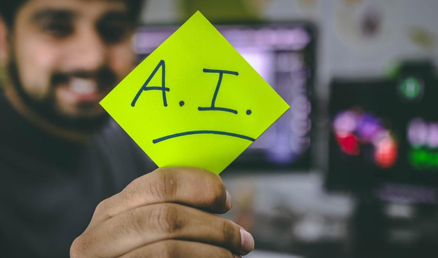 Post-It gehalten von einer Hand mit dem Kürzel A.I.