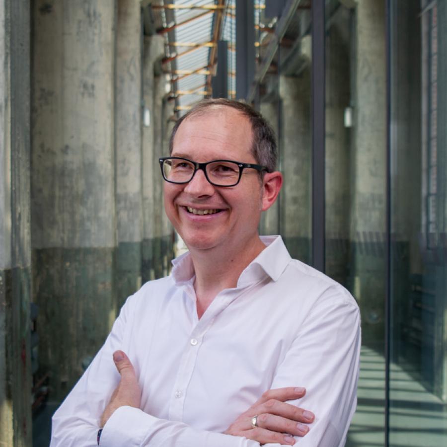 Markus Vossel Mittelalter Mann mit Brille und weißem Hemd im schrägen Halbportrait in einer Industriehalle