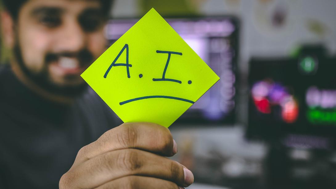 Post-It gehalten von einer Hand mit dem Kürzel A.I.